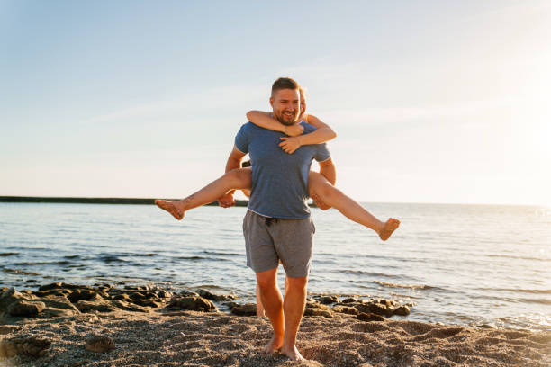 istock Dad rides his daughter on back on the seashore. 1354329881