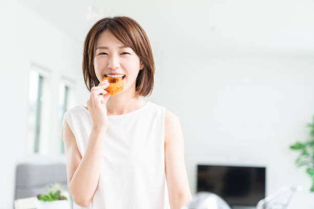 istock attractive asian woman eating donuts 1354332953