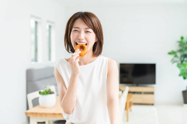istock attractive asian woman eating donuts 1354332995
