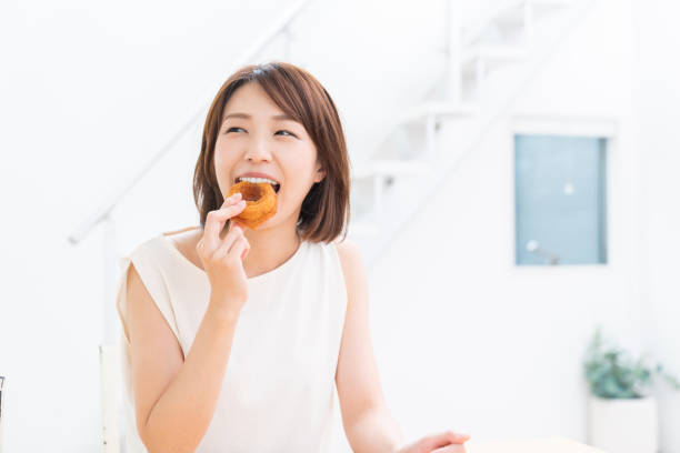 istock attractive asian woman eating donuts 1354333018