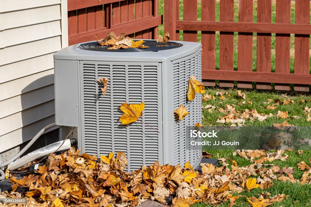 Dirty air conditioning unit covered in leaves during autumn. Home air conditioning, HVAC, repair, service, fall cleaning and maintenance. background, no people Air Conditioner Stock Photo