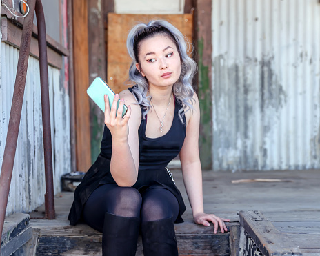 Rock and roll teenage girl in black leather skirt taking selfie