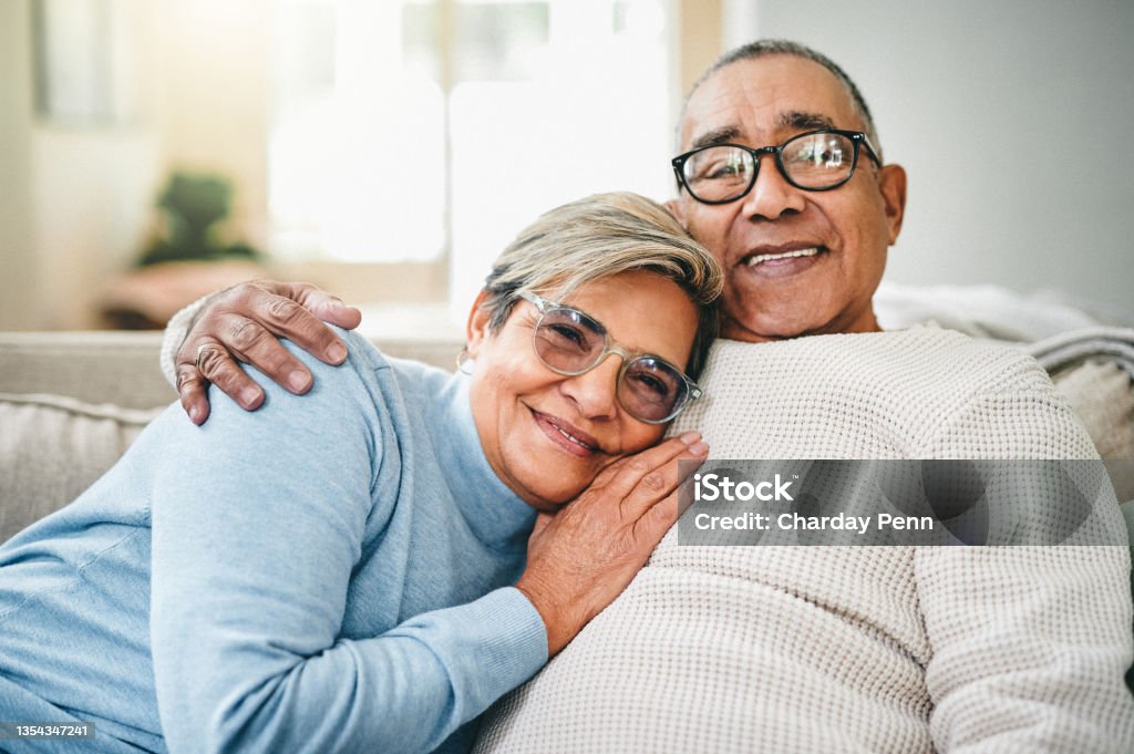 Shot of a senior couple relaxing on the couch at home I'm happiest in his arms Senior Couple Stock Photo