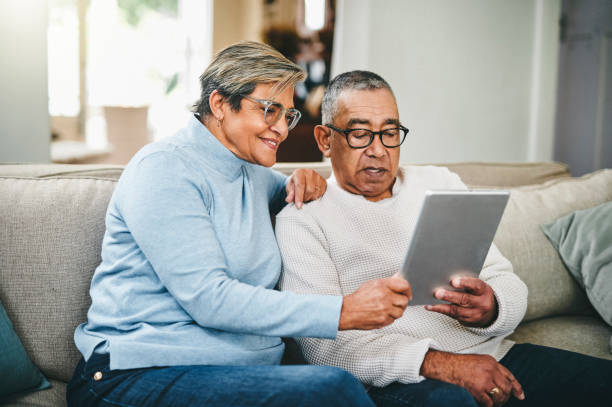 aufnahme eines älteren paares mit einem digitalen tablet zu hause - senior adult couple computer retirement stock-fotos und bilder