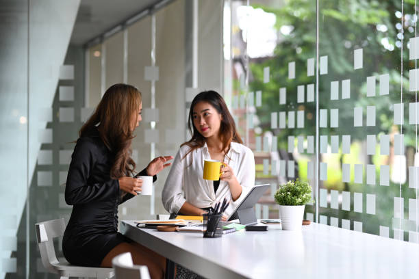 istock Two business colleagues having coffee break and talking each other in office. 1354349721