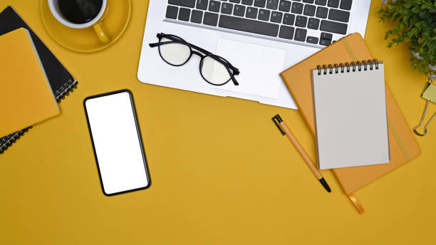 istock Above view  laptop computer, cup of coffee, notebook and glasses on yellow background. 1354350432