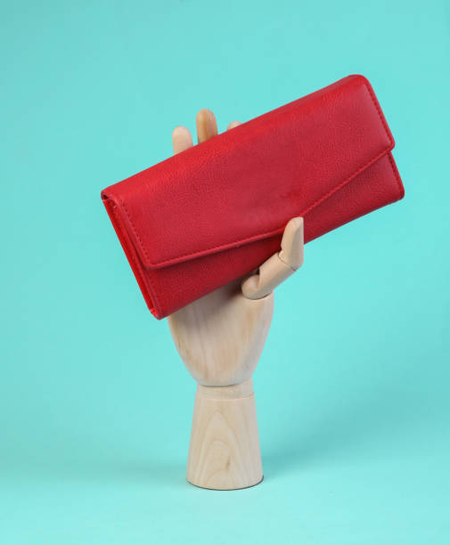 istock Wooden hand holds red leather wallet on blue background 1354361134