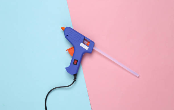 istock Glue gun with glue stick on a pink blue background. 1354361307