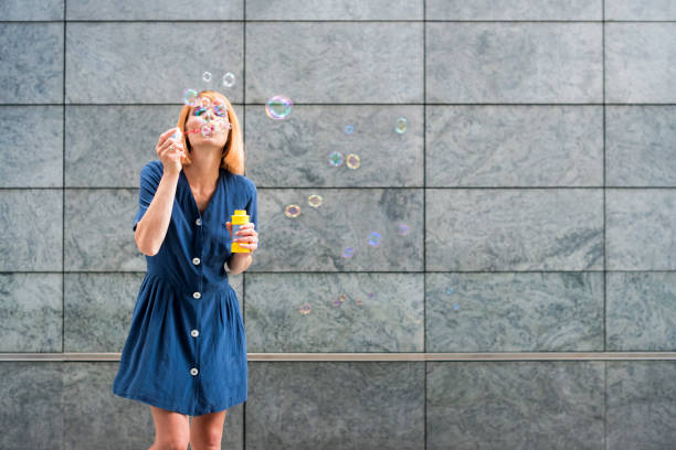 istock Young woman blowing soap bubbles 1354366218