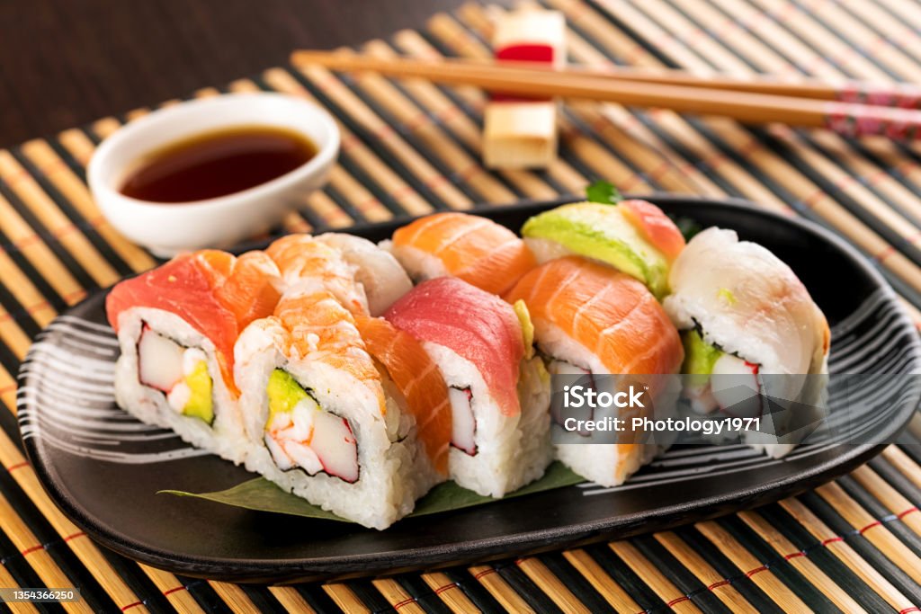 Set of rainbow uramaki sushi rolls with avocado Set of rainbow uramaki sushi rolls with tuna, salmon and avocado, served in restaurant on bamboo mat Sushi Stock Photo