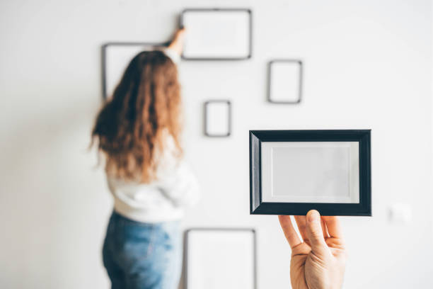 istock Couple hanging picture frame on wall in new house 1354367444