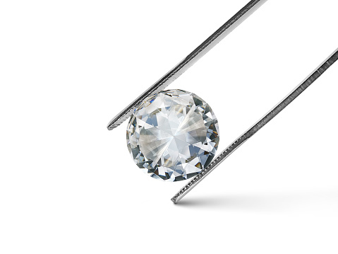 diamante talla brillante sostenido por pinzas aisladas sobre fondo blanco photo