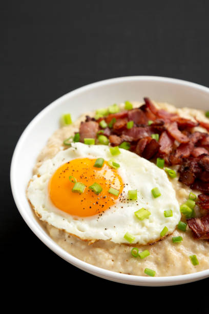 istock Homemade Cheesy Bacon Savory Oatmeal Bowl on a black background, side view. 1354374014