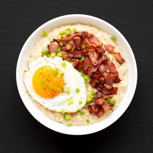istock Homemade Cheesy Bacon Savory Oatmeal Bowl on a black surface, top view. Overhead, from above, flat lay. 1354374533