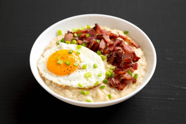 istock Homemade Cheesy Bacon Savory Oatmeal Bowl on a black surface, side view. 1354374636