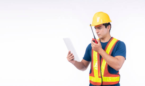 istock Maintenance workman occupation technology concept. Handsome confident craftsman wear yellow helmet hard hat safety talking with walkie talkie while looking tablet standing over isolated background. 1354375760