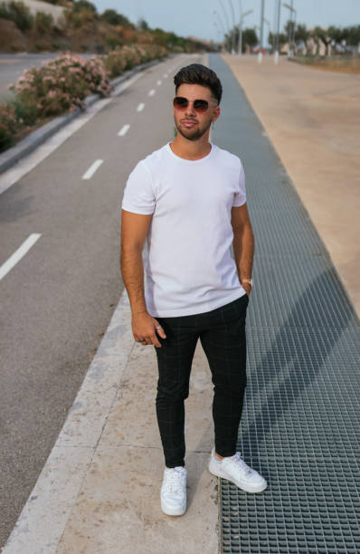 istock Pretty man with sunglasses standing on a sidewalk looking away 1354376588