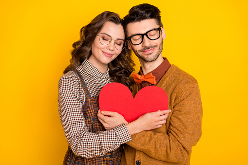 Portrait of attractive cheerful amorous couple friends friendship embracing heart shape isolated on bright yellow color background.