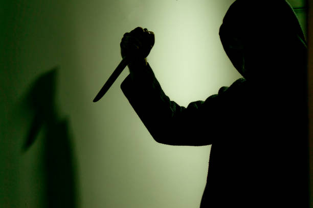 hd стоковая фотография грабителя, входящего в дом, убийцы, преследующего в тени и темноте, с ножом и пистолетом, силуэт убийцы. - burglary thief fear burglar стоковые фото и изображения