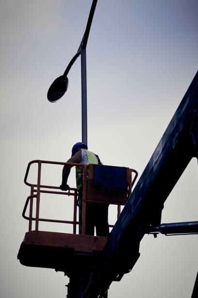 istock Manual worker on a telescopic lifter basket fixing street light pole. 1354380923