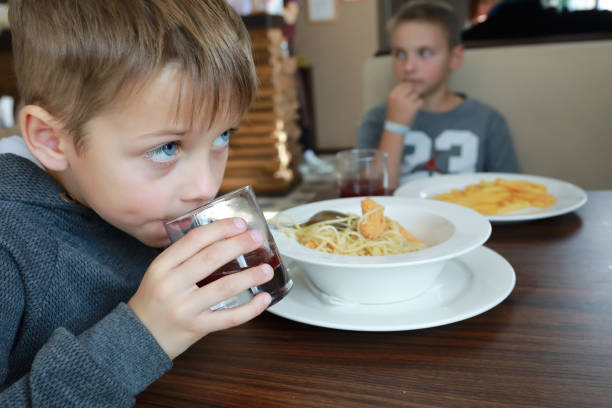 istock Child drinking juice in cafe 1354381884