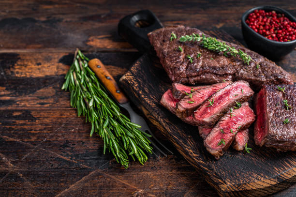 grilled sliced skirt beef meat steak on a cutting board with herbs. dark wooden background. top view. copy space - picanha beef meat rare imagens e fotografias de stock