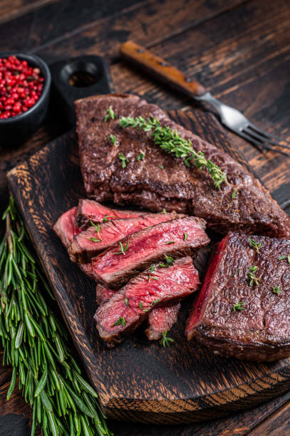 grilled sliced skirt beef meat steak on a cutting board with herbs. dark wooden background. top view - picanha beef meat rare imagens e fotografias de stock