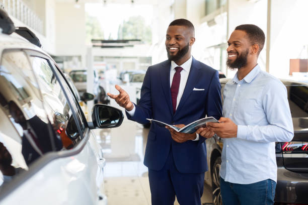 venditore nero che pubblicizza una nuova automobile al cliente maschio nel centro di concessionaria auto - car african descent shopping car dealership foto e immagini stock