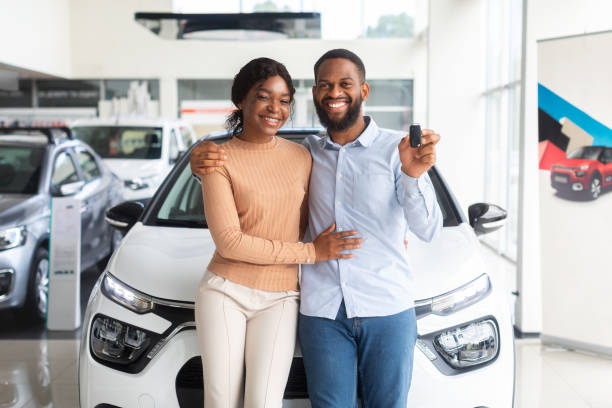ディーラーセンターで手に車のキーでポーズをとって幸せな黒いカップル - car african descent shopping car dealership ストックフォトと画像