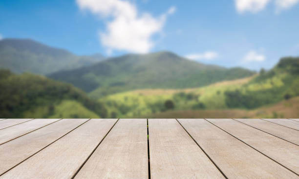 istock Empty old wooden table in front of blurred beautiful mountain view, forest and cloud on blue sky at country side on clear day. Can be used for display or montage for show your product. 1354385854