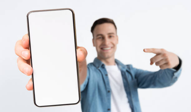 istock Stylish young man holding big smartphone with empty screen 1354385925