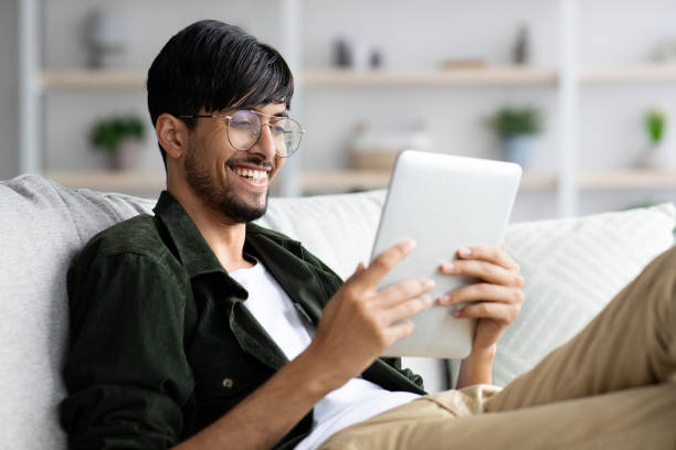 istock Relaxed middle-eastern young man chilling at home with digital tablet 1354385951