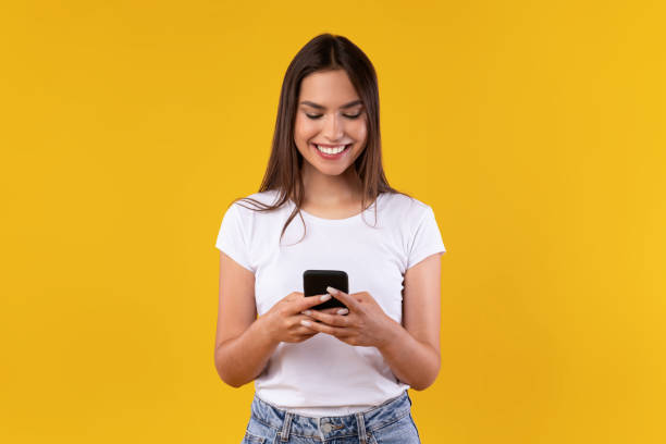 istock Happy excited lady using mobile phone at yellow studio 1354387038