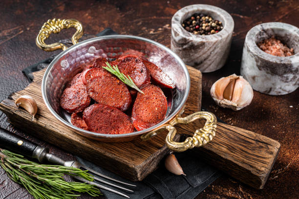 Turkish fried sausage sucuk in a pan. Dark background. Top view Turkish fried sausage sucuk in a pan. Dark background. Top view. turkish sausage stock pictures, royalty-free photos & images