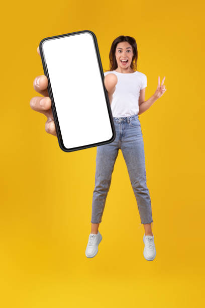 istock Woman showing white empty smartphone screen and jumping up 1354388305