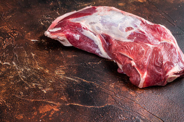 istock Raw lamb mutton shoulder meat on the bone. Dark background. Top view. Copy space 1354388539