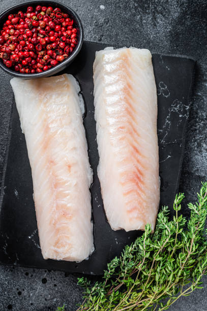 istock Raw cod loin fillet fish on marble board. Black background. Top view 1354388666