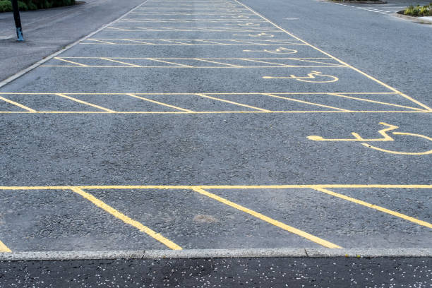 istock Numerous empty yellow marked disable vehicle parking spaces in a car park 1354389702