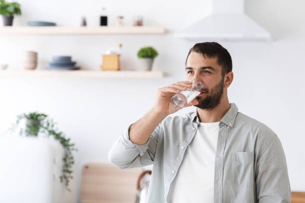 attraente maschio europeo di mezza età in acqua potabile informale dal vetro all'interno minimalista della cucina - house home interior water glass foto e immagini stock