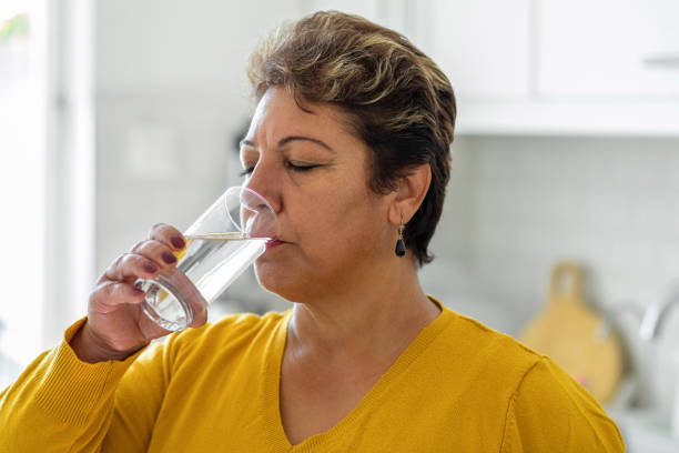 mujer bebiendo de un vaso de agua - sediento fotografías e imágenes de stock