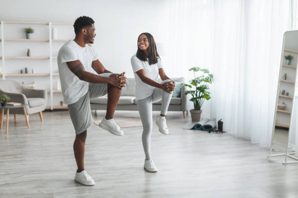 joven pareja negra haciendo ejercicio de rodilla alta - stretching boyfriend indoors lifestyles fotografías e imágenes de stock