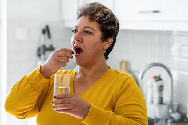istock Mature woman taking pill in the kitchen 1354390783