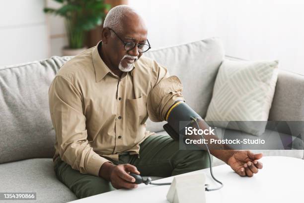 Senior African Male Measuring Arterial Blood Pressure Having Hypertension Indoor Stock Photo - Download Image Now