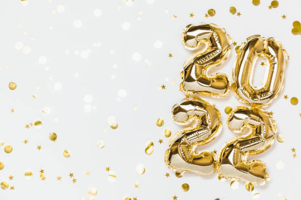 New year 2022 balloon celebration card. Gold foil helium balloon number 2022, party decoration, gold confetti stars on white background. Flat lay, merry christmas, happy holidays concept. stock photo