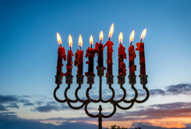 Festive menorah and burning wax candles Festive menorah and burning wax candles as symbol of Hanukkah - Jewish Holiday of Miracle Light, morning colorful blurred sky hanukkah candles stock pictures, royalty-free photos & images