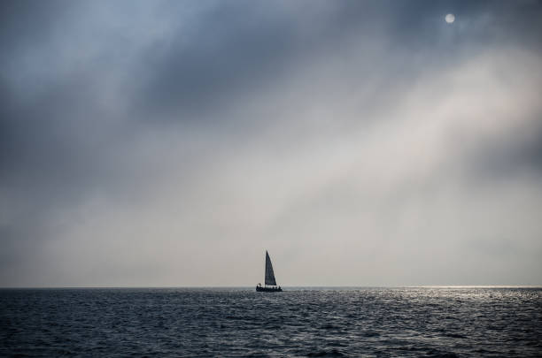 istock Sailing ship yacht in open sea at sundown with cloudy stormy sky 1354400210