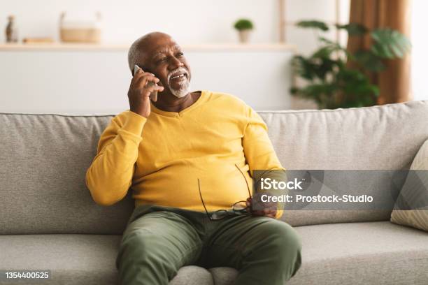 Senior African American Man Talking On Cellphone Sitting At Home Stock Photo - Download Image Now