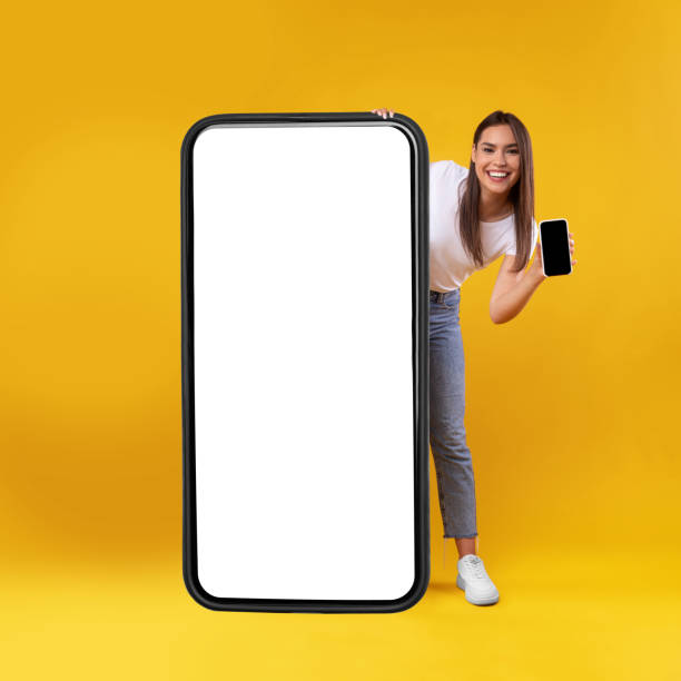 istock Woman holding empty smartphone screen, peeking out big panel 1354400715