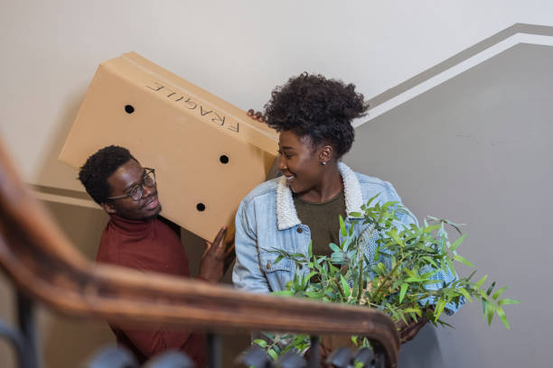 couple moving into new home carrying box upstairs - upstairs imagens e fotografias de stock