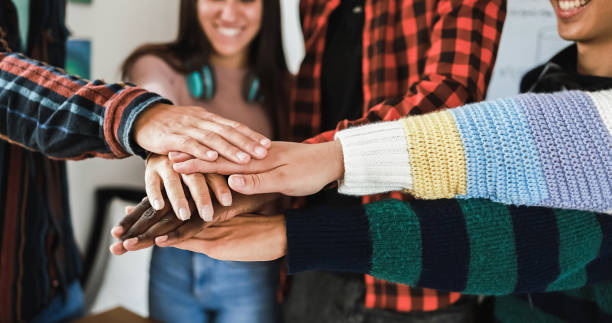 istock Multiracial young group of friends celebrating together stacking hands inside school room - Focus on hands 1354405983
